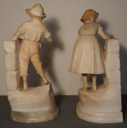 Pair of Circa 1925 Italian Art Deco Enrico Brunelleschi Carved Two-Tone Alabaster Figural Young Boy and Girl by Stone Wall Bookends